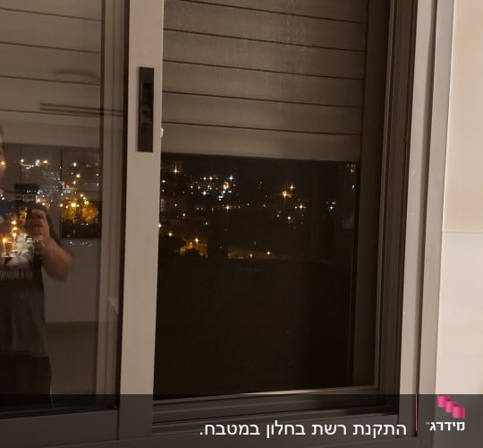 חלון אלומיניום עם תריסים סגורים בלילה